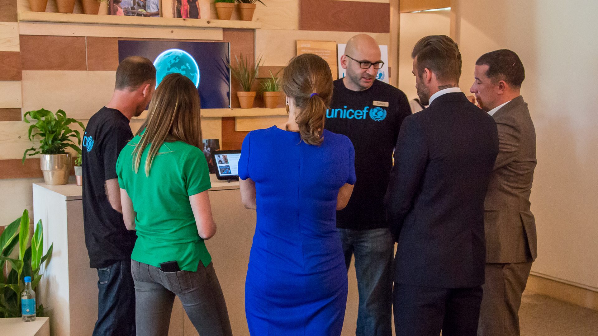 The 3D globe rendered on a wall screen, guests gathered around the tablet controller